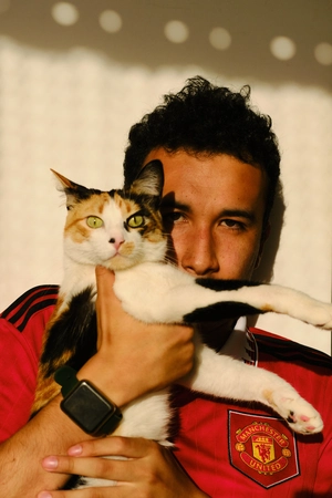 Kevin Rodríguez (thekevshot) holding a calico cat in a Manchester United shirt